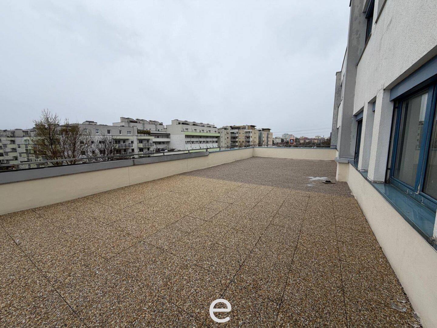 Große Dachterrasse mit weitem Blick über die Stadt und umliegende Gebäude, ideal für Entspannung.