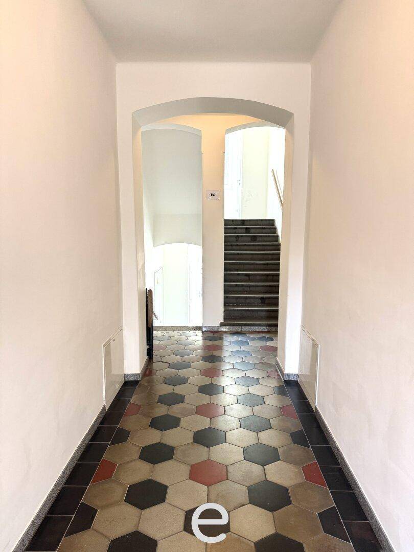 Eingangsbereich mit historischem Fliesenboden und Treppenaufgang.