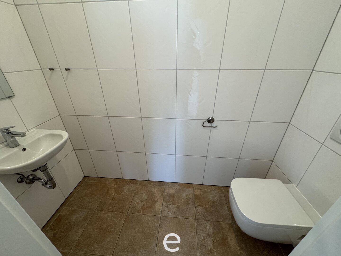 Kleines Gäste-WC mit Wand-WC und Waschbecken, komplett gefliest.