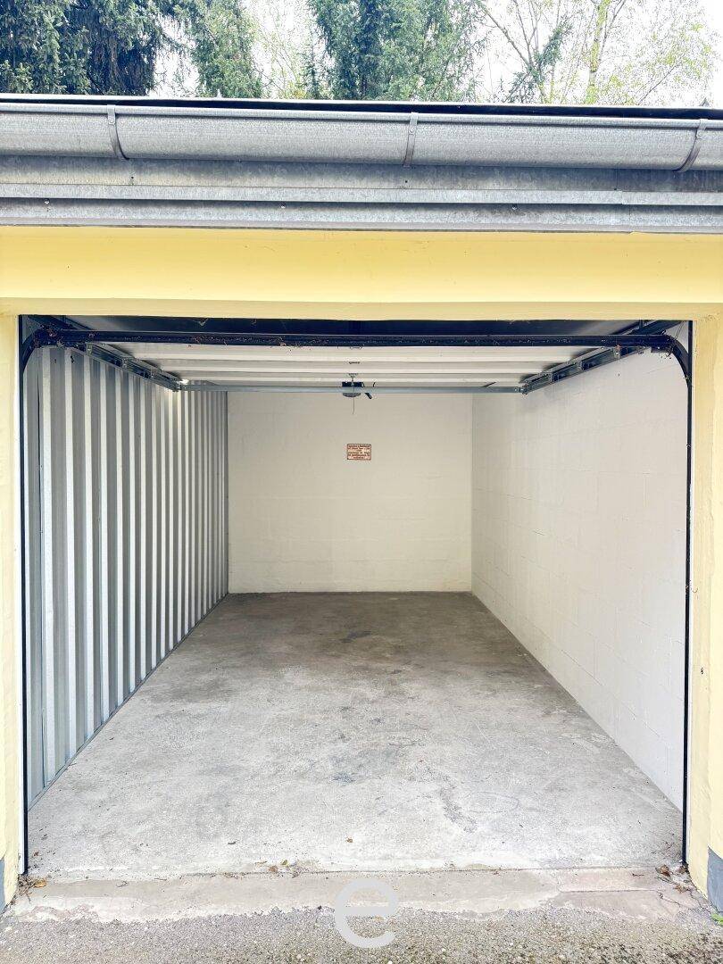 Leere Einzelgarage mit Betonboden und gelbem Garagentor.