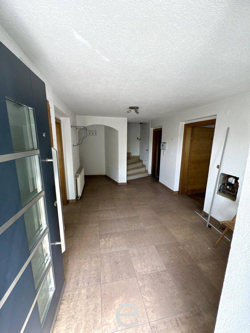 Heller Eingangsbereich mit Fliesenboden, Garderobe und Treppenaufgang.