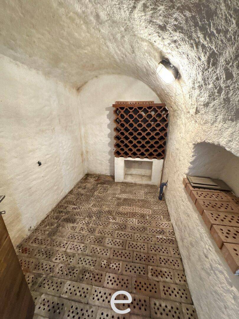 Rustikaler Weinkeller mit Ziegelboden, gewölbter Decke und Weinregalen.