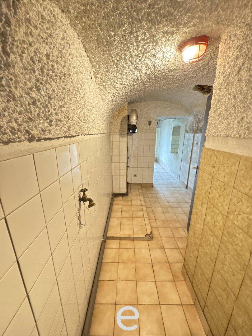 Gekachelter Kellerflur mit gewölbter Decke und einfacher Beleuchtung.