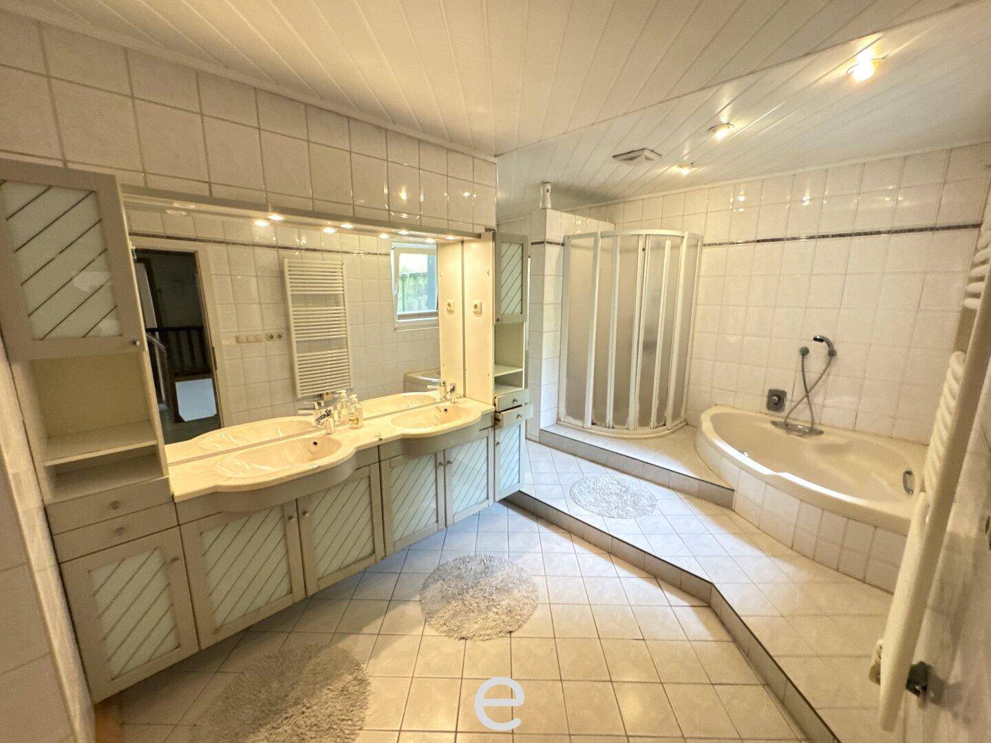 Geräumiges Badezimmer mit Doppelwaschbecken, Eckbadewanne und Duschkabine.