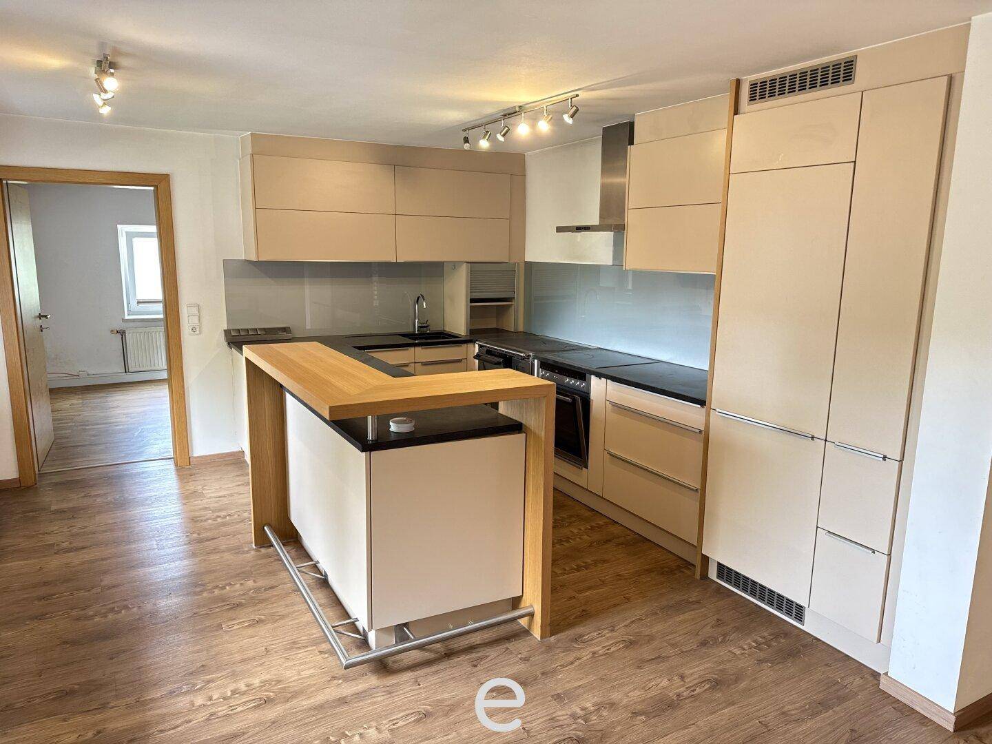 Moderne Einbauküche mit heller Holzoptik, Kücheninsel und integrierten Geräten.