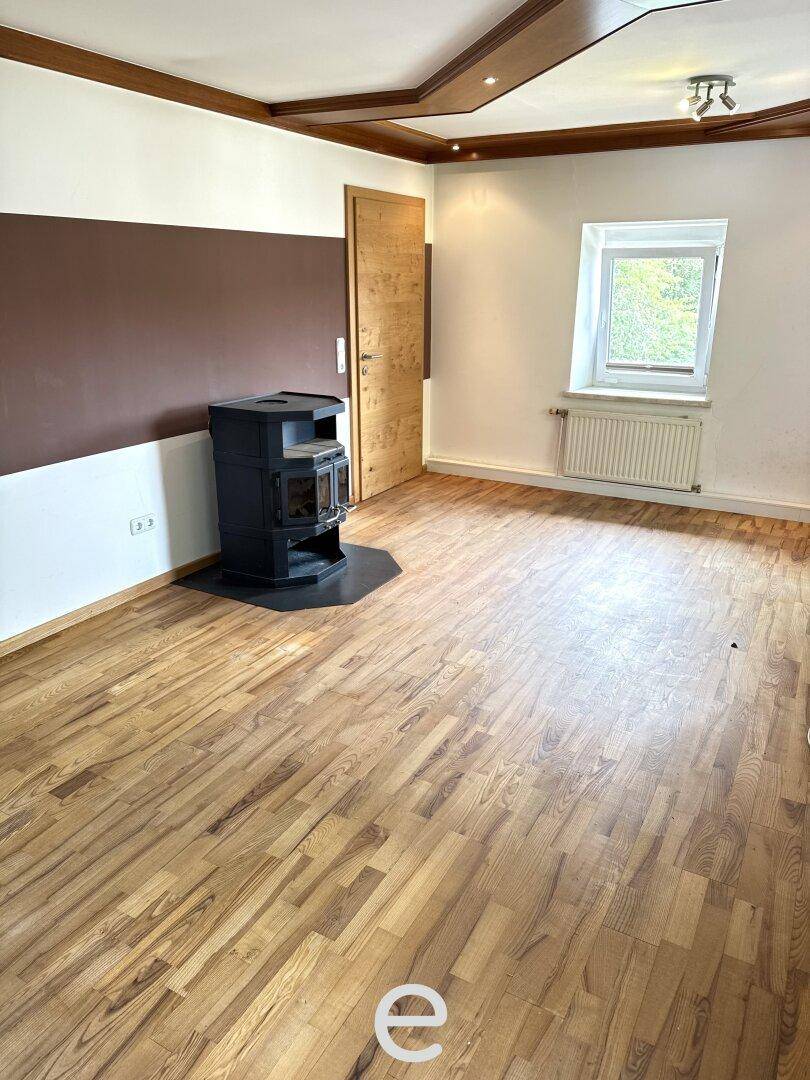 Gemütlicher Raum mit Holzboden, Kaminofen und Holzdecke, ideal als Wohn- oder Schlafzimmer.