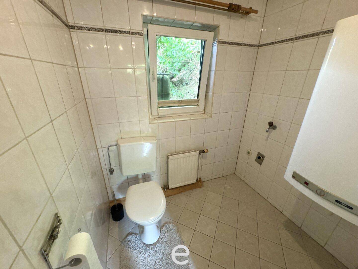 Kleines WC mit Fenster, Toilette und Heizkörper, einfach gefliest.