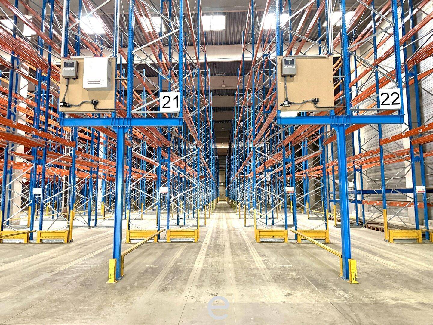 Detaillierte Ansicht der leeren, farbigen Hochregalsysteme in der modernen Lagerhalle, bereit für die Bestückung.