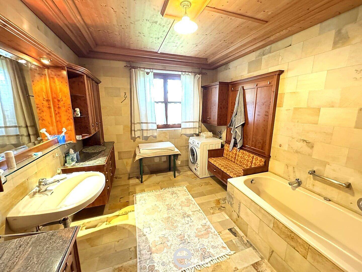 Rustikales Badezimmer mit Holzbalkendecke, Badewanne und Waschmaschine.