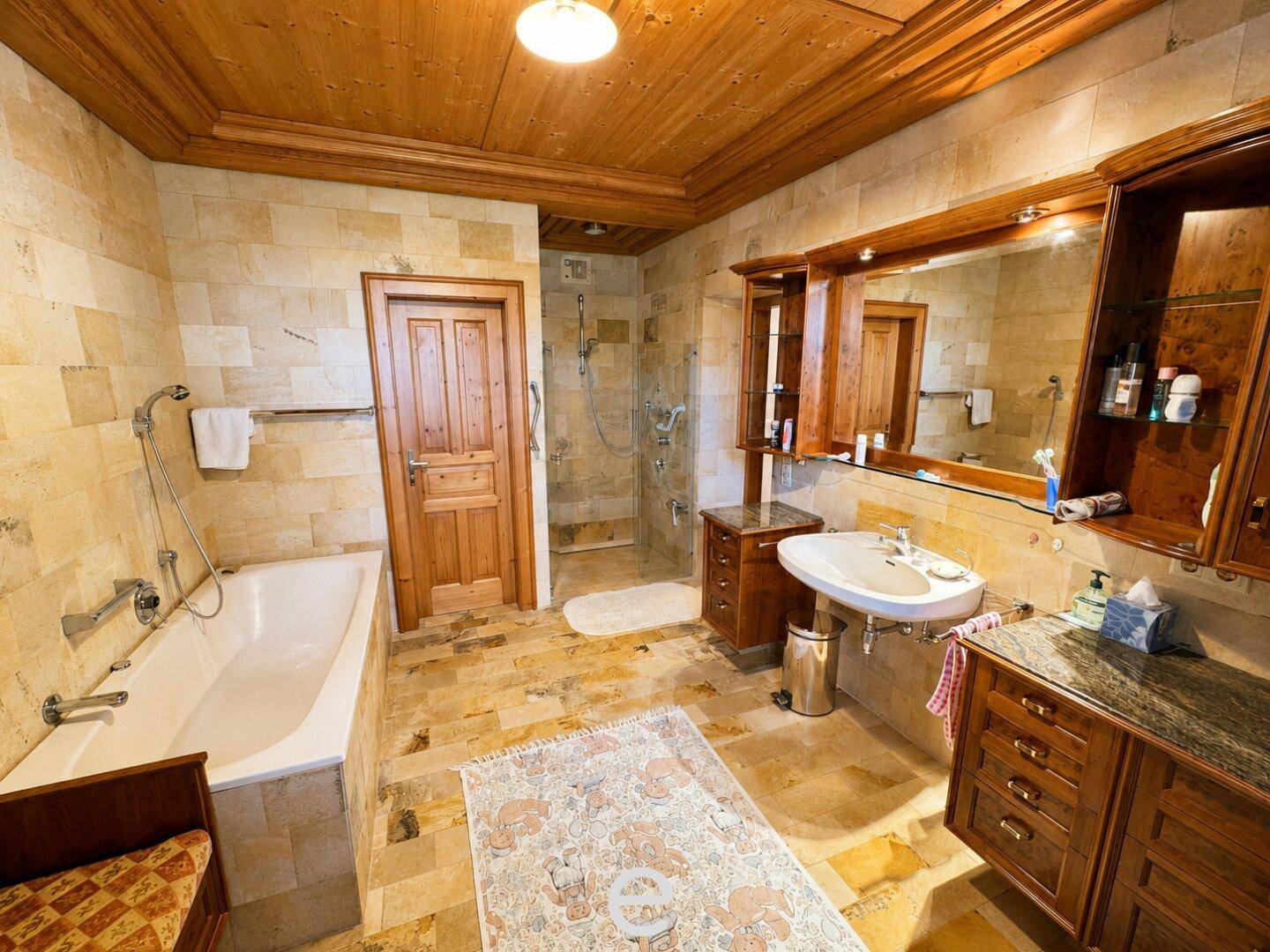 Geräumiges Badezimmer mit Badewanne, Dusche und rustikalen Steinfliesen.