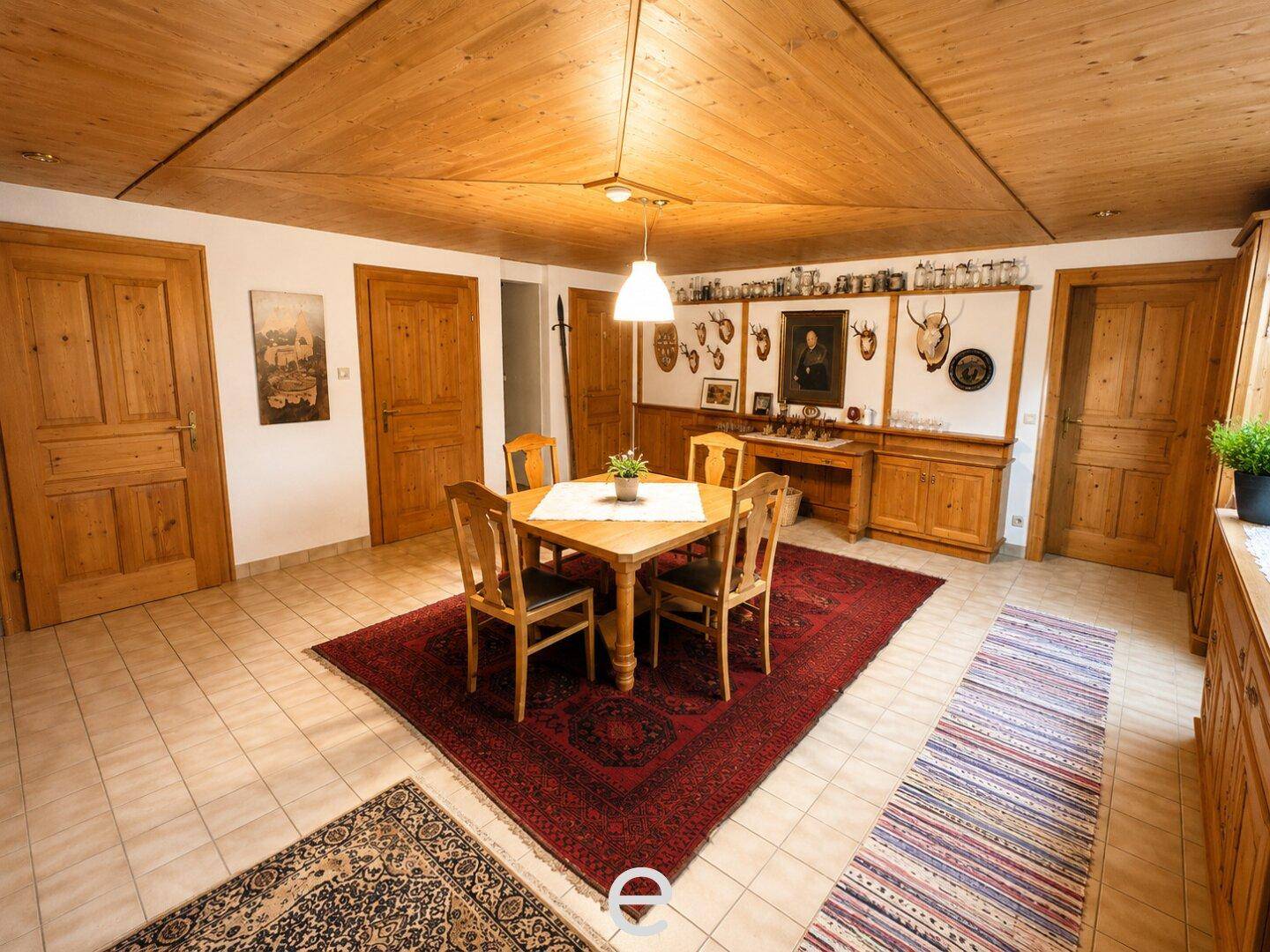 Geräumiger Essbereich mit Holztüren, traditionellem Teppich und Jagdtrophäen an der Wand.