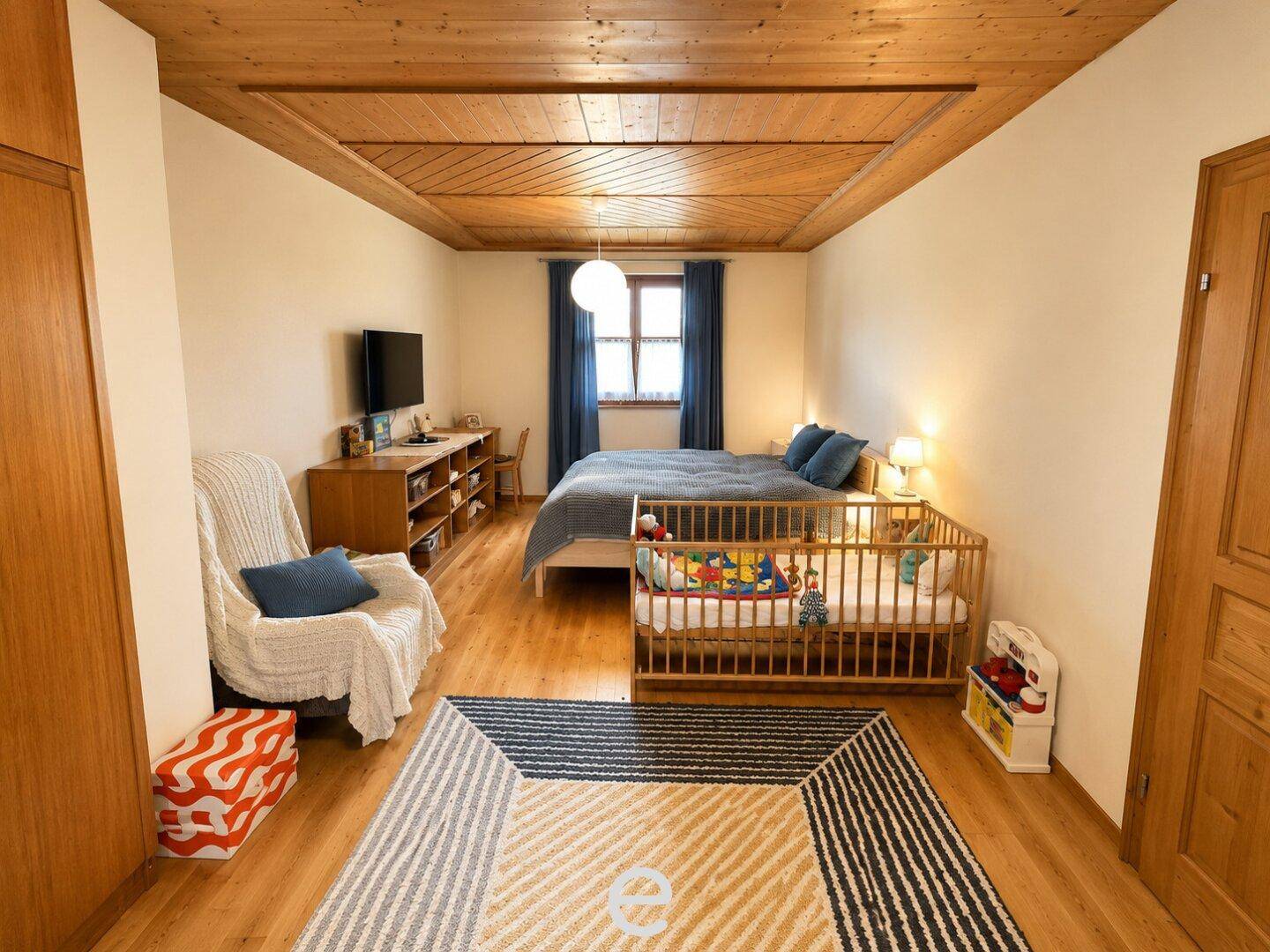 Gemütliches Schlafzimmer mit Holzboden, Holzdecke und Kinderbett.