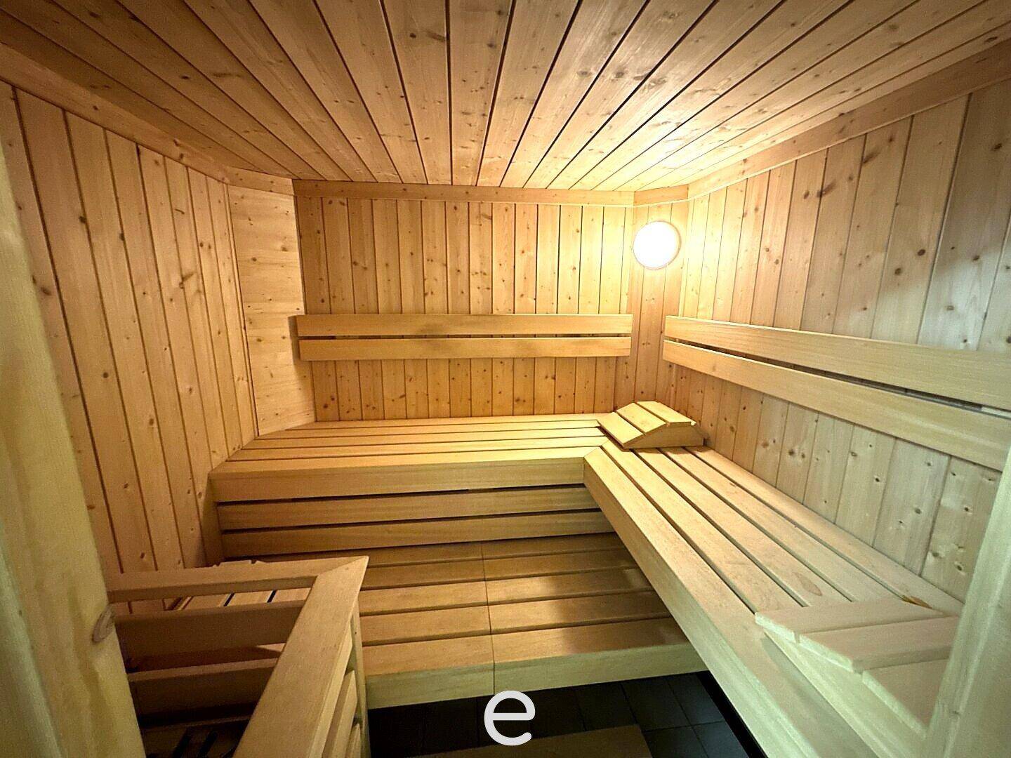 Traditionelle Holzsauna mit mehreren Sitzbänken und stimmungsvoller Beleuchtung.