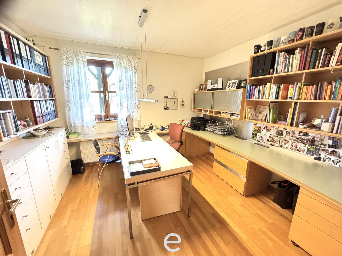 Großes Arbeitszimmer mit viel Stauraum, Schreibtischen und Holzboden.