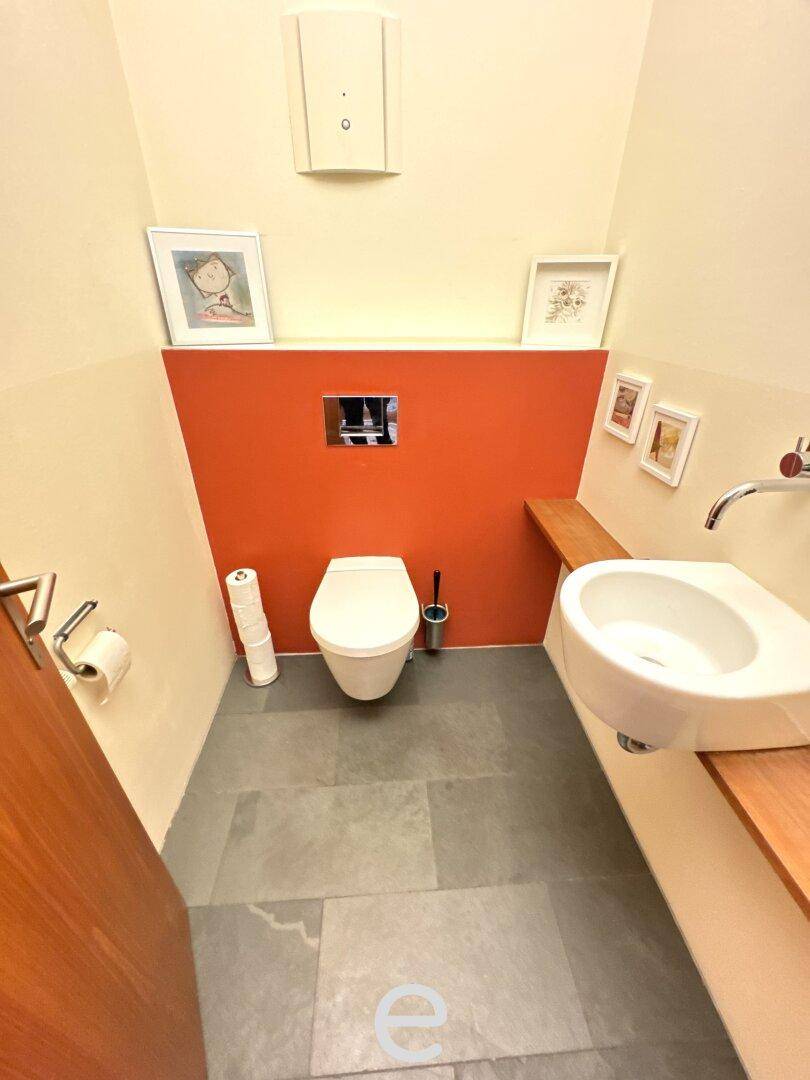 Modernes Gäste-WC mit Wand-WC, Waschbecken und farbiger Akzentwand.