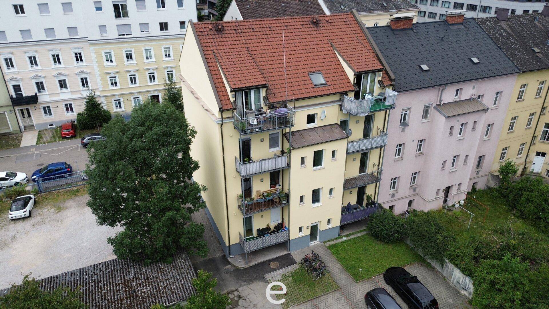Rückansicht des Mehrfamilienhauses mit mehreren Balkonen und einem kleinen Gartenbereich.