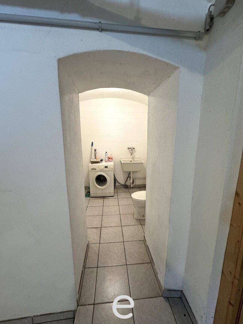Schmaler Durchgang führt zu einem praktischen Waschraum mit WC und Waschmaschine.