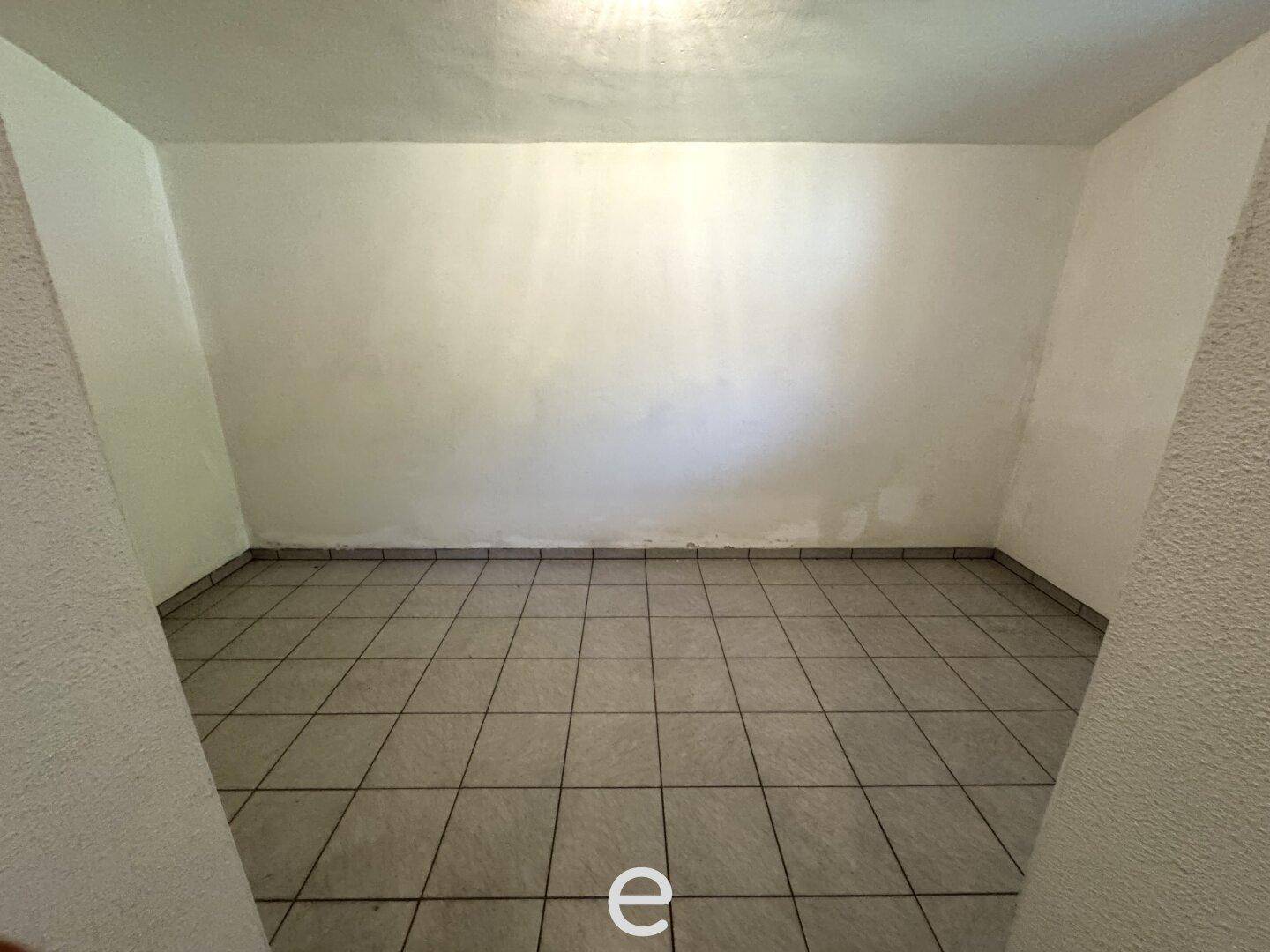 Einfacher Kellerraum mit Fliesenboden und weißen Wänden, ideal als Abstellfläche.