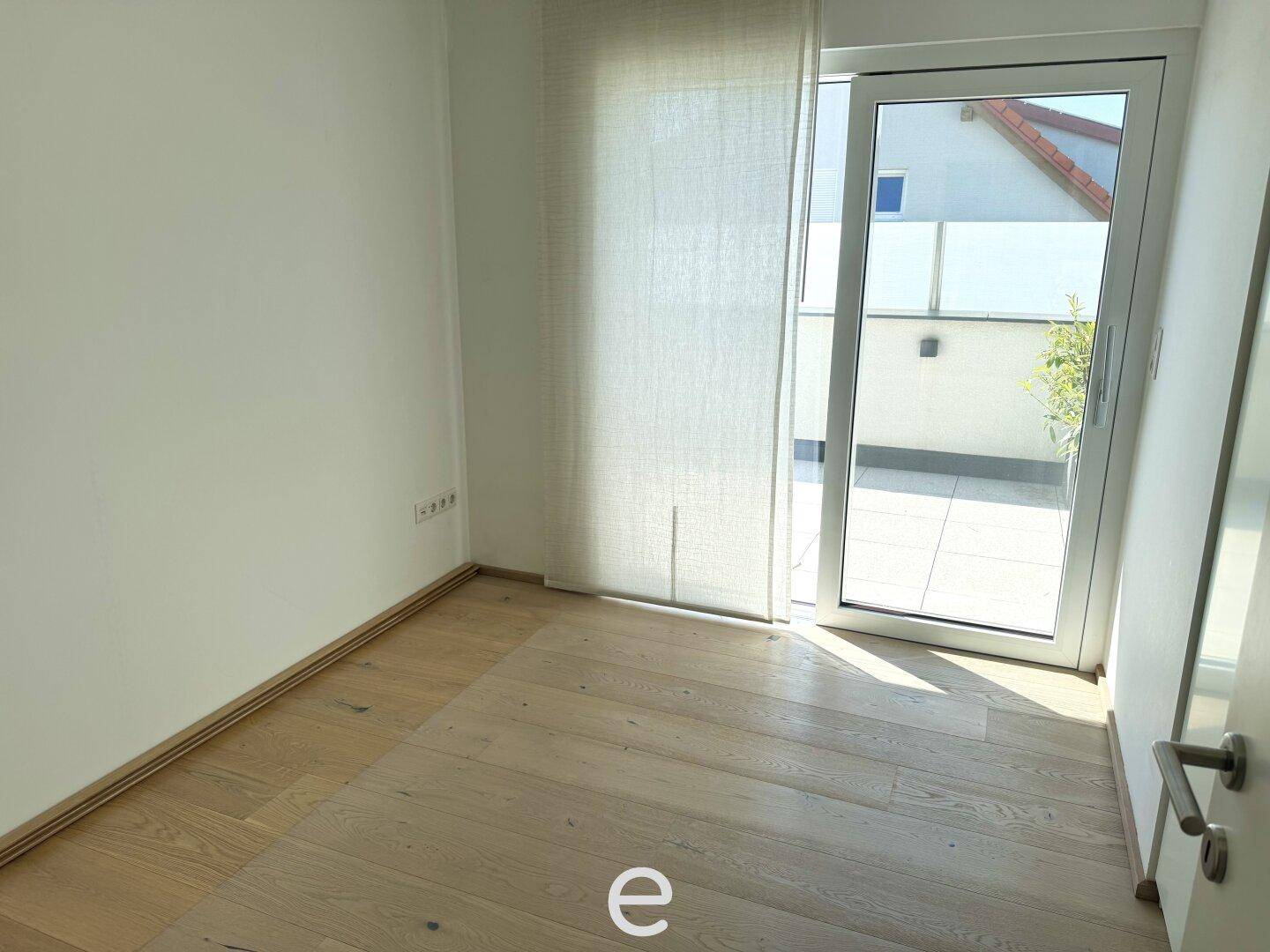 Helles Zimmer mit Holzboden und direktem Zugang zu einem sonnigen Außenbereich.