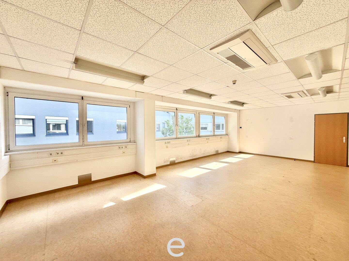 Helles, leeres Büro mit großen Fenstern und Linoleumboden, ideal für verschiedene Nutzungen.