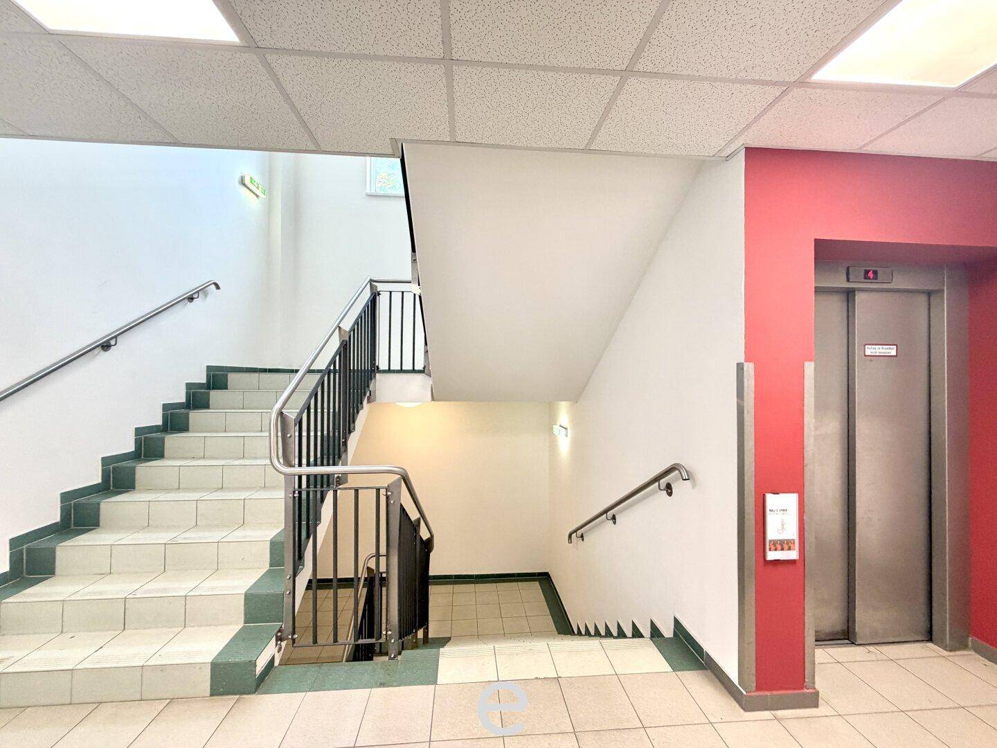 Treppenhaus mit Geländer und einem Aufzug, der Zugang zu den oberen Etagen bietet.