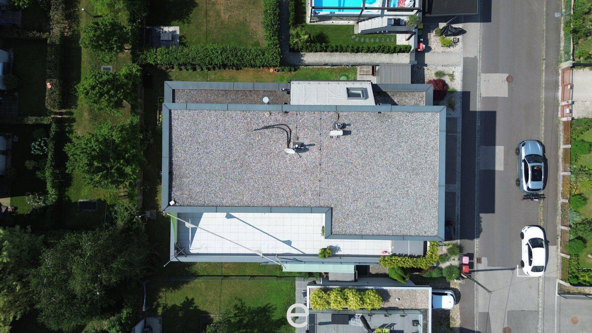 Draufsicht auf das Gebäude mit Flachdach und umliegenden Grundstücken.