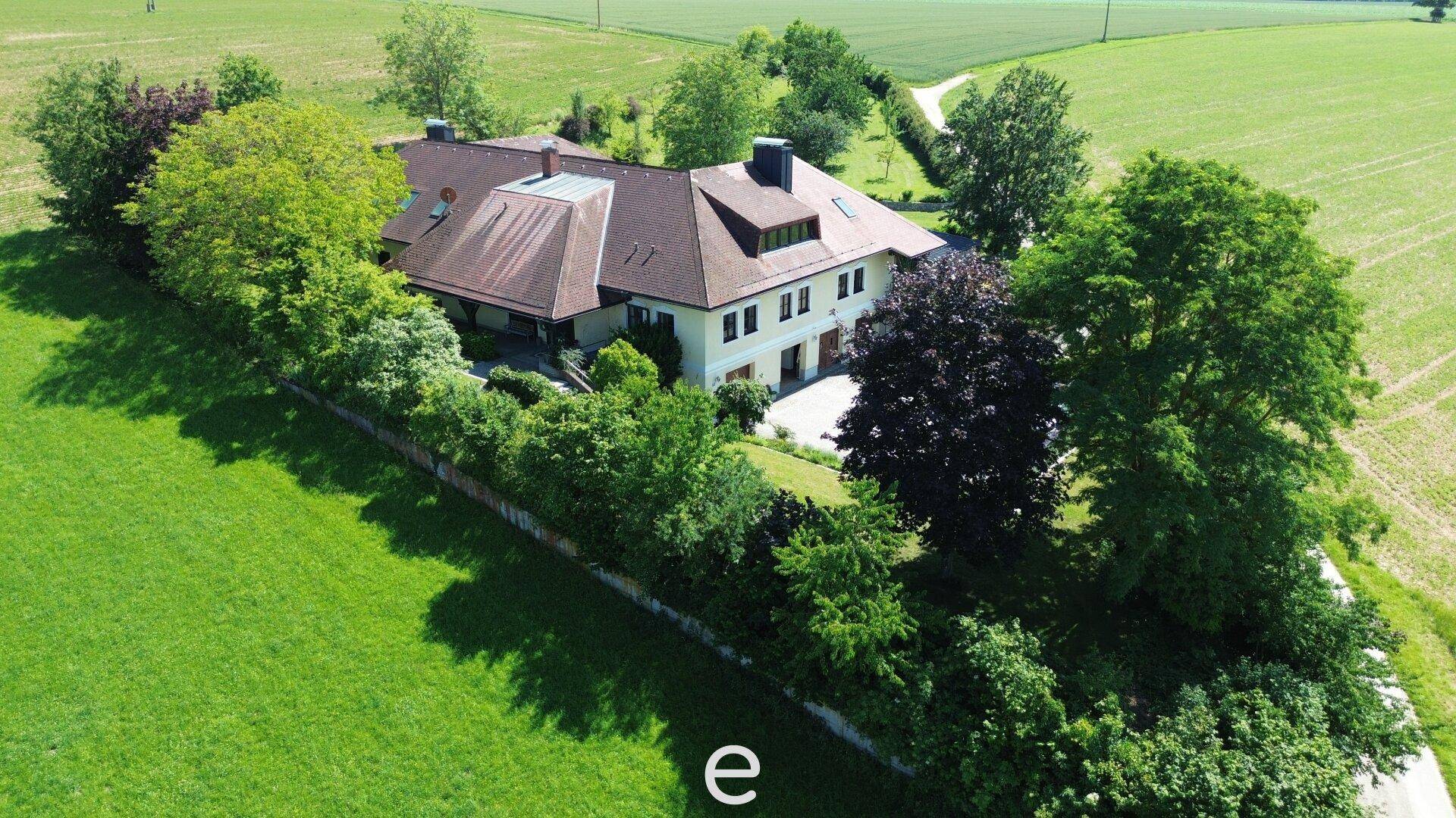 Anwesen eingebettet in eine weitläufige grüne Landschaft mit Feldern und Bäumen.