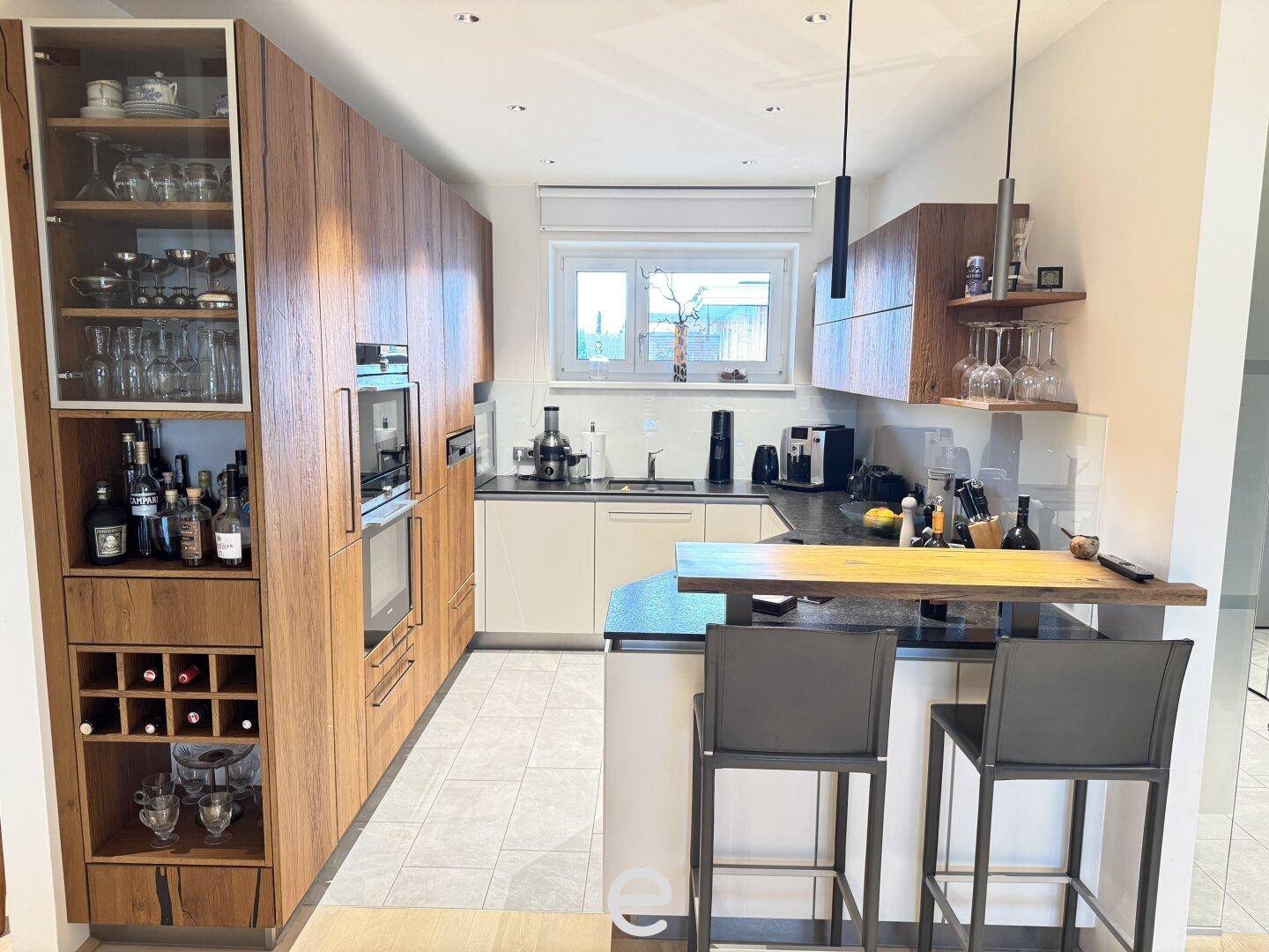 Moderne Küche mit Holzelementen, integrierten Geräten und einer Frühstücksbar für geselliges Kochen.