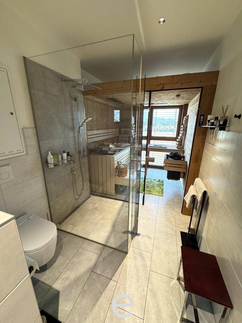 Modernes Badezimmer mit begehbarer Dusche, WC und direktem Zugang zur privaten Sauna.