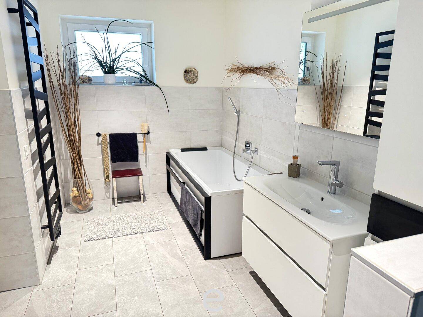 Helles Badezimmer mit Badewanne, modernem Waschtisch und beheiztem Handtuchhalter.