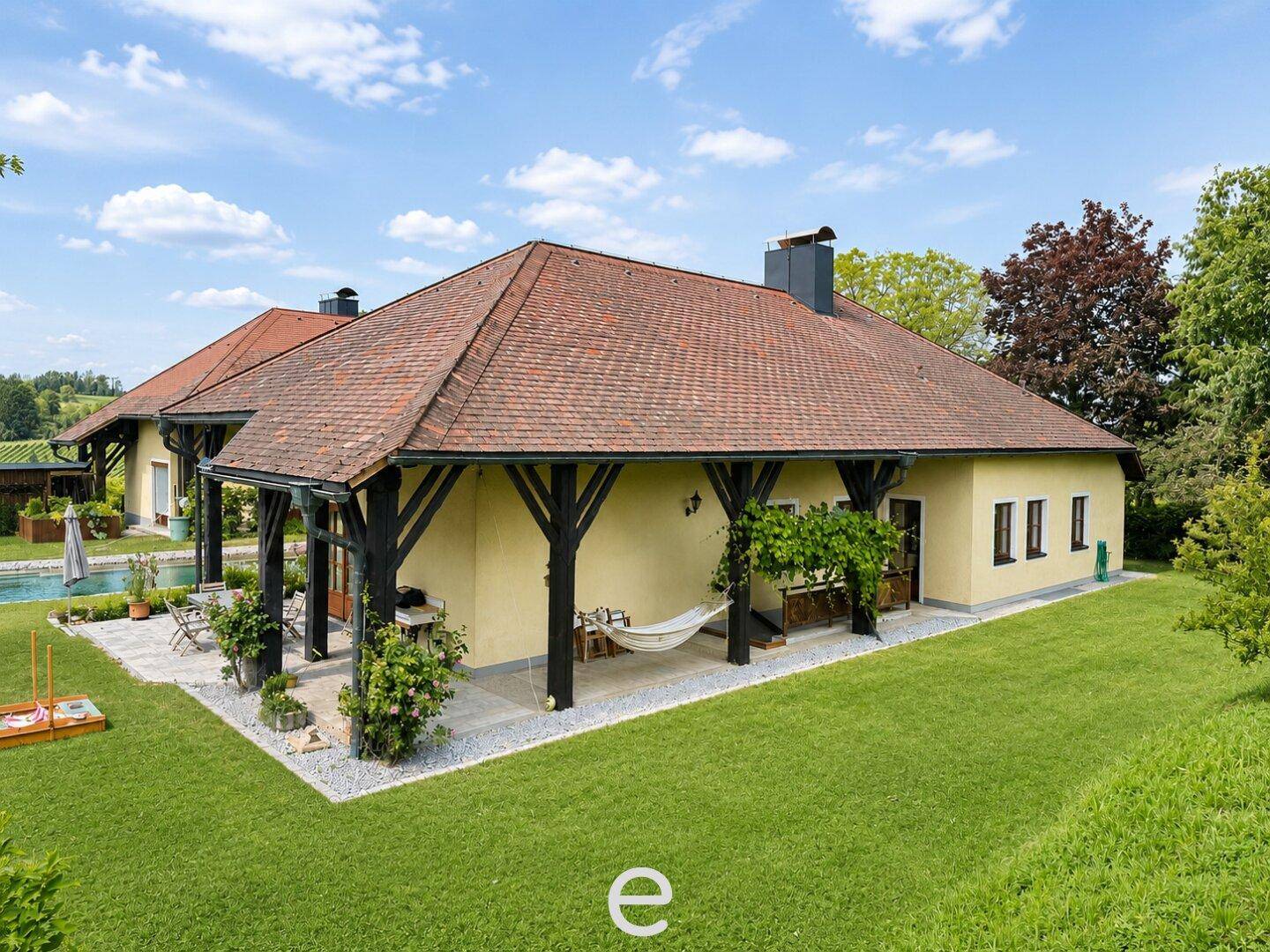 Rückseite des Hauses mit überdachter Terrasse, Hängematte und Blick auf den Garten.