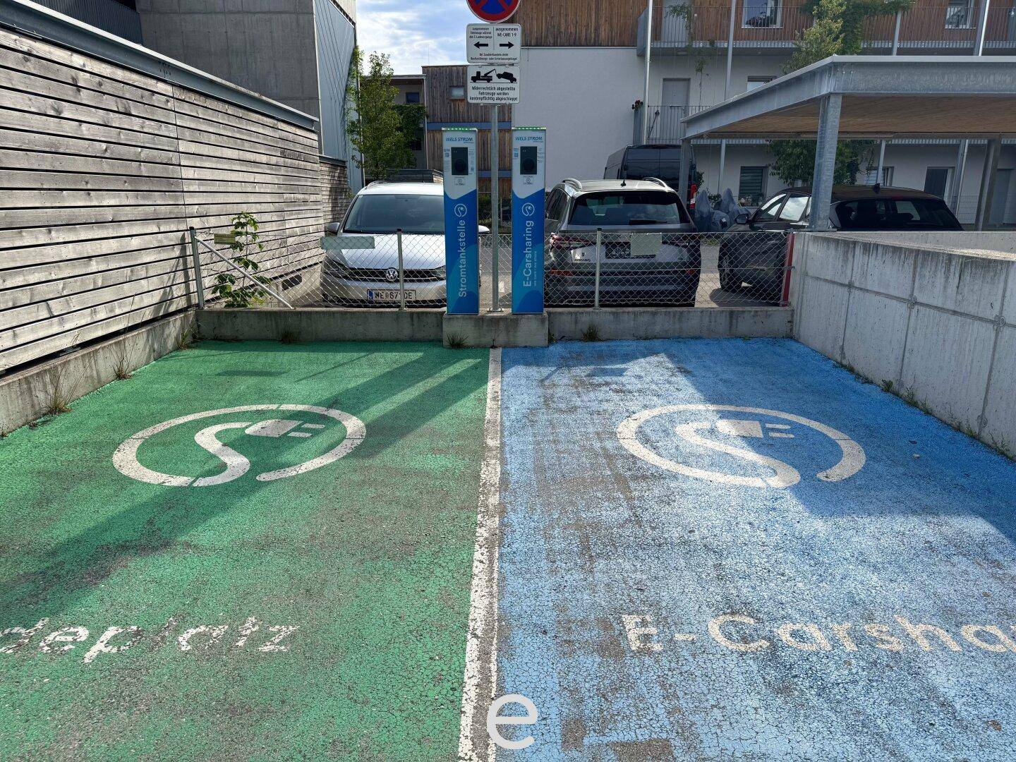 Zwei markierte Parkplätze mit Ladestationen für Elektrofahrzeuge und Carsharing-Möglichkeiten.