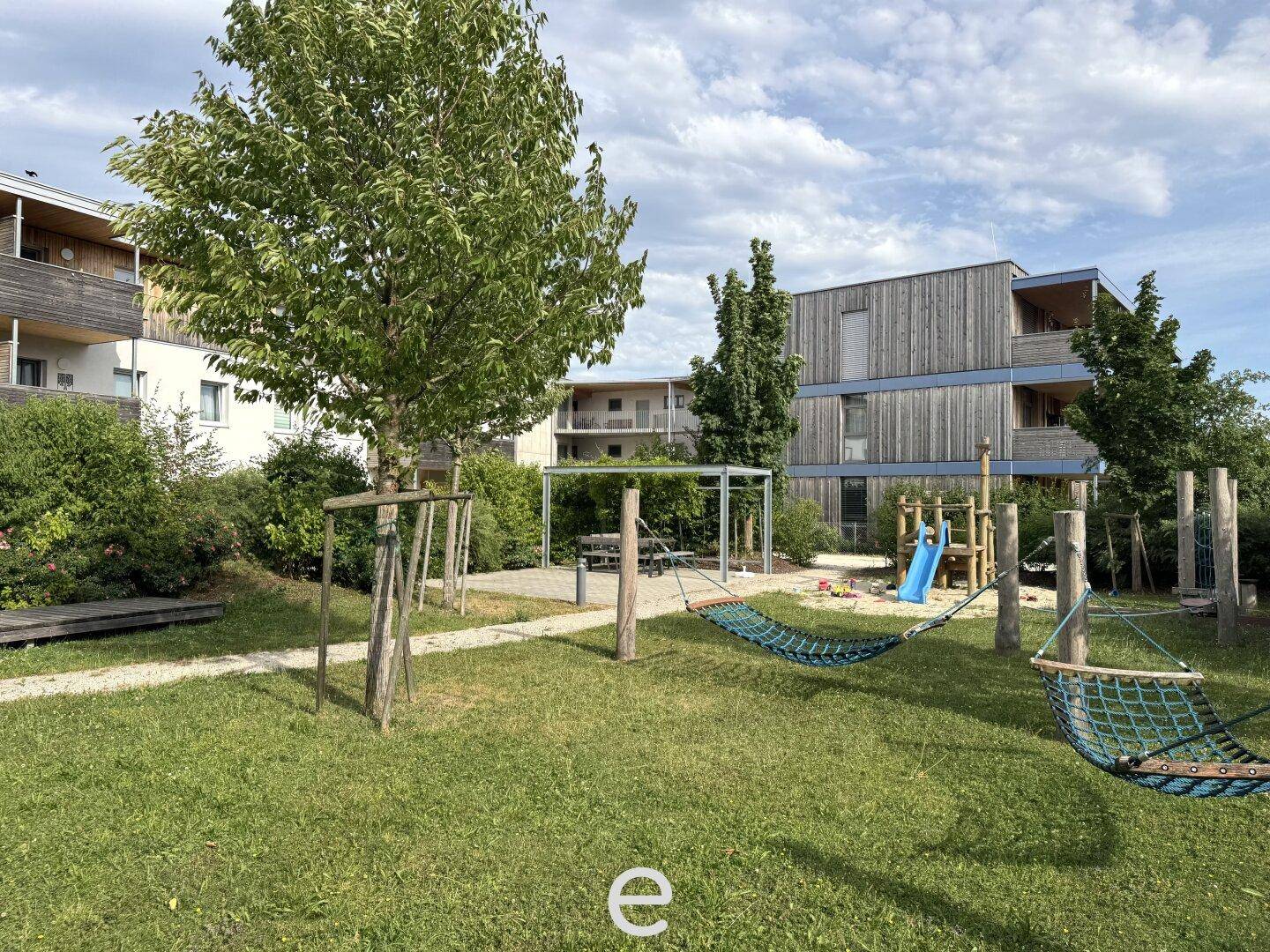 Grüner Spielplatz mit Schaukeln, Rutsche und Hängematten, ideal für Kinder und Entspannung.