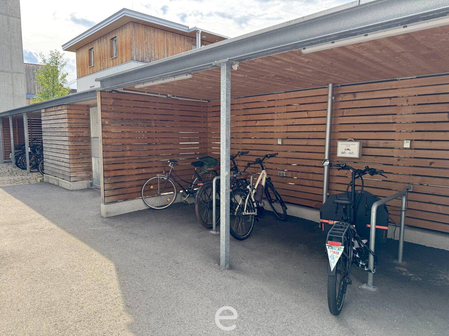 Überdachte Fahrradabstellplätze mit Holzverkleidung, bieten sicheren Schutz für Fahrräder.