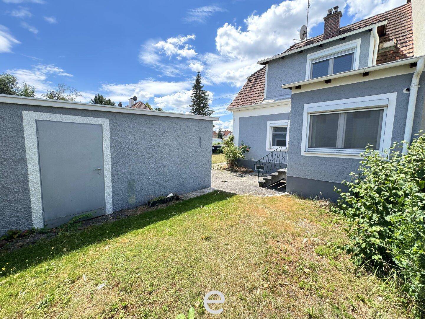 Kleiner Gartenbereich hinter dem Haus mit Rasenfläche und einem Nebengebäude.