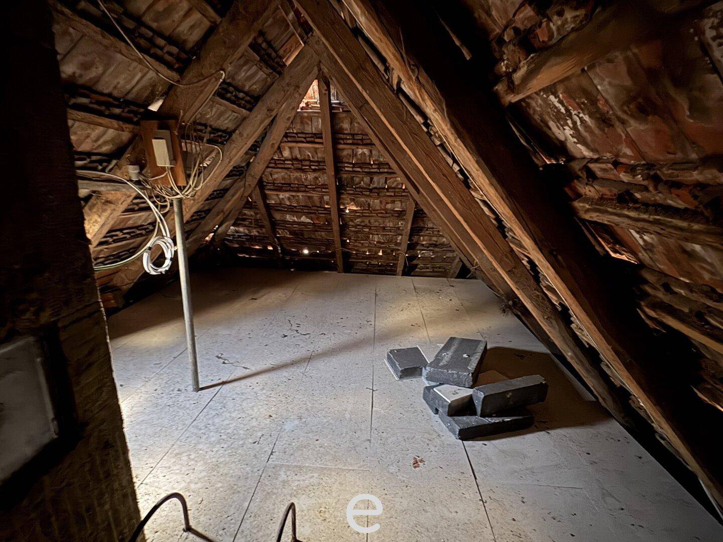 Unausgebauter Dachboden mit sichtbarer Holzkonstruktion und Ziegeln, bietet Ausbaupotenzial.
