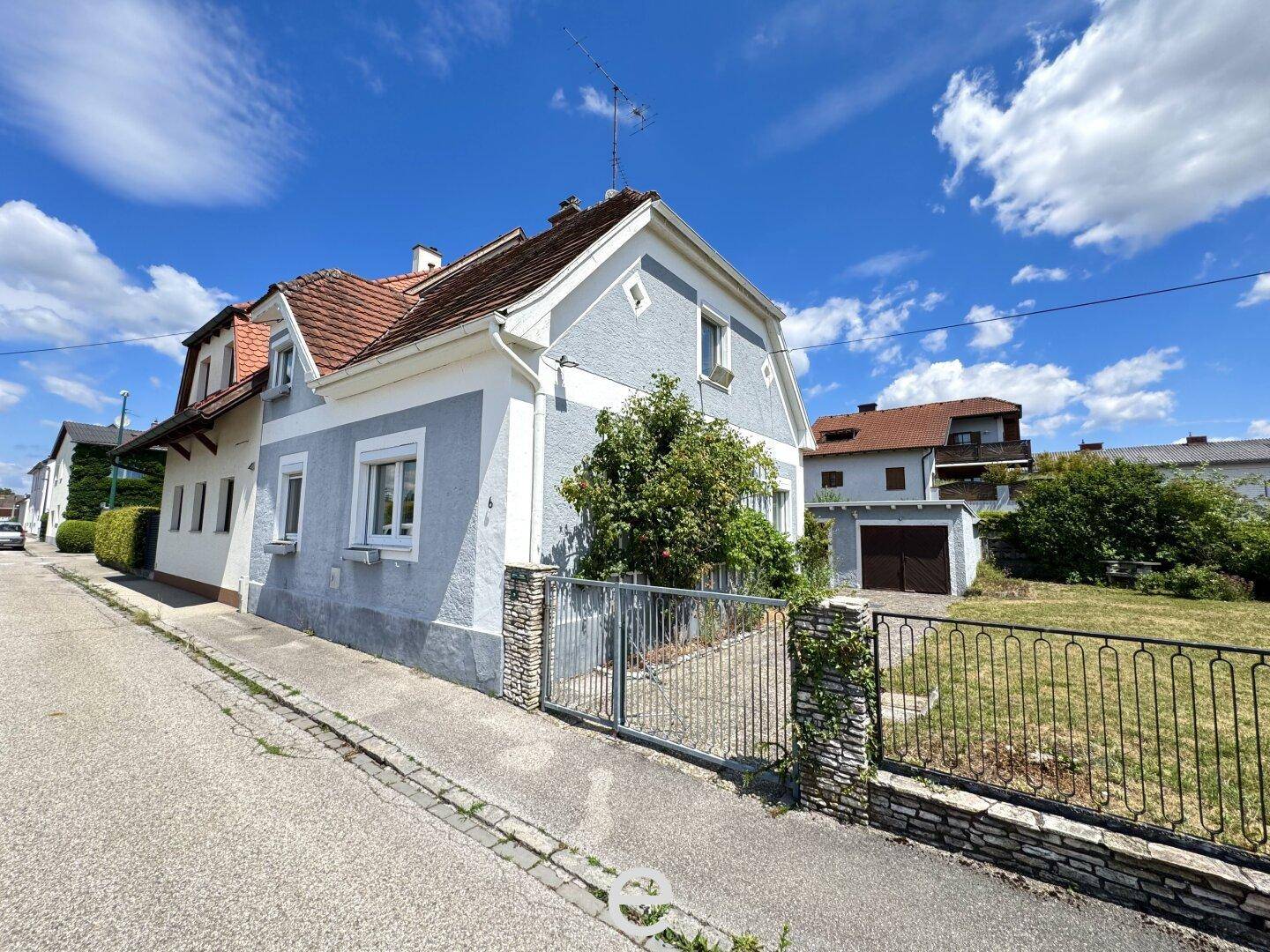 Ansicht des Einfamilienhauses von der Straße aus mit Vorgarten und Zaun.