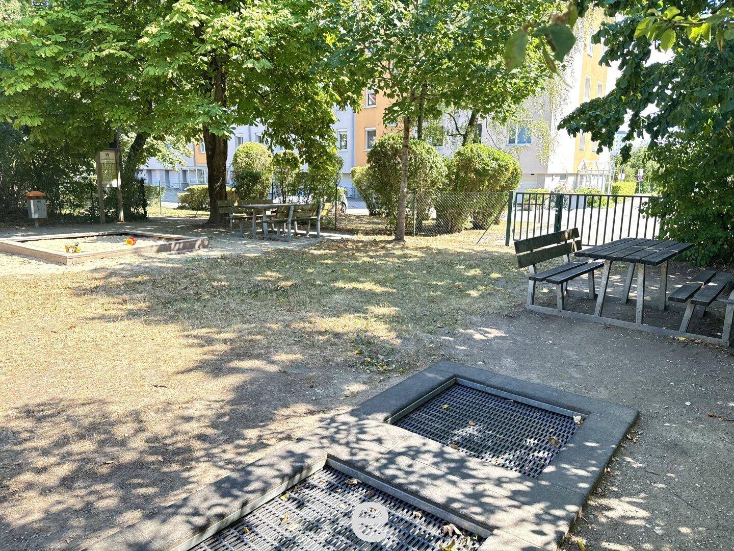 Gemeinschaftlicher Gartenbereich mit Spielplatz, Sandkasten, Trampolin und Sitzgelegenheiten im Grünen.