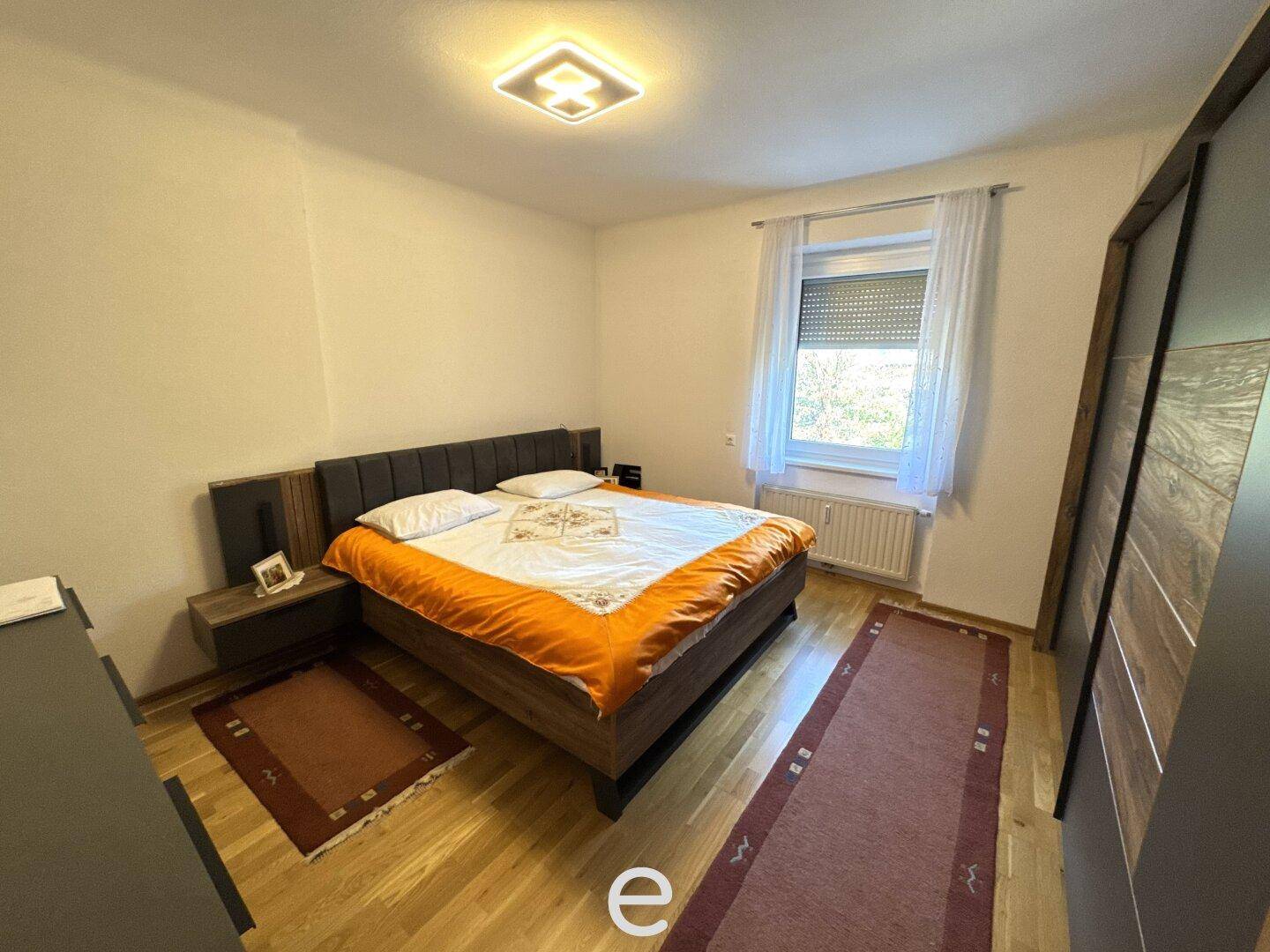 Gemütliches Schlafzimmer mit Doppelbett, Holzboden und einem Fenster für natürliches Licht.