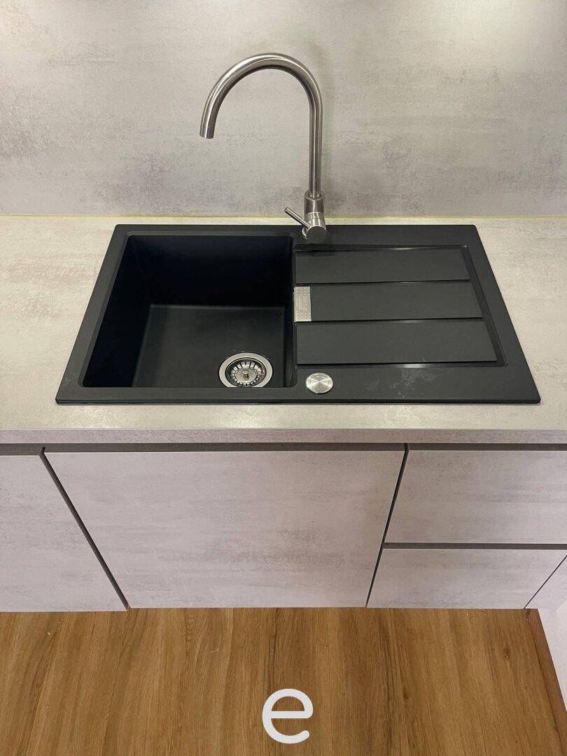 Schwarzes Spülbecken mit modernem Wasserhahn in der grauen Küchenzeile.