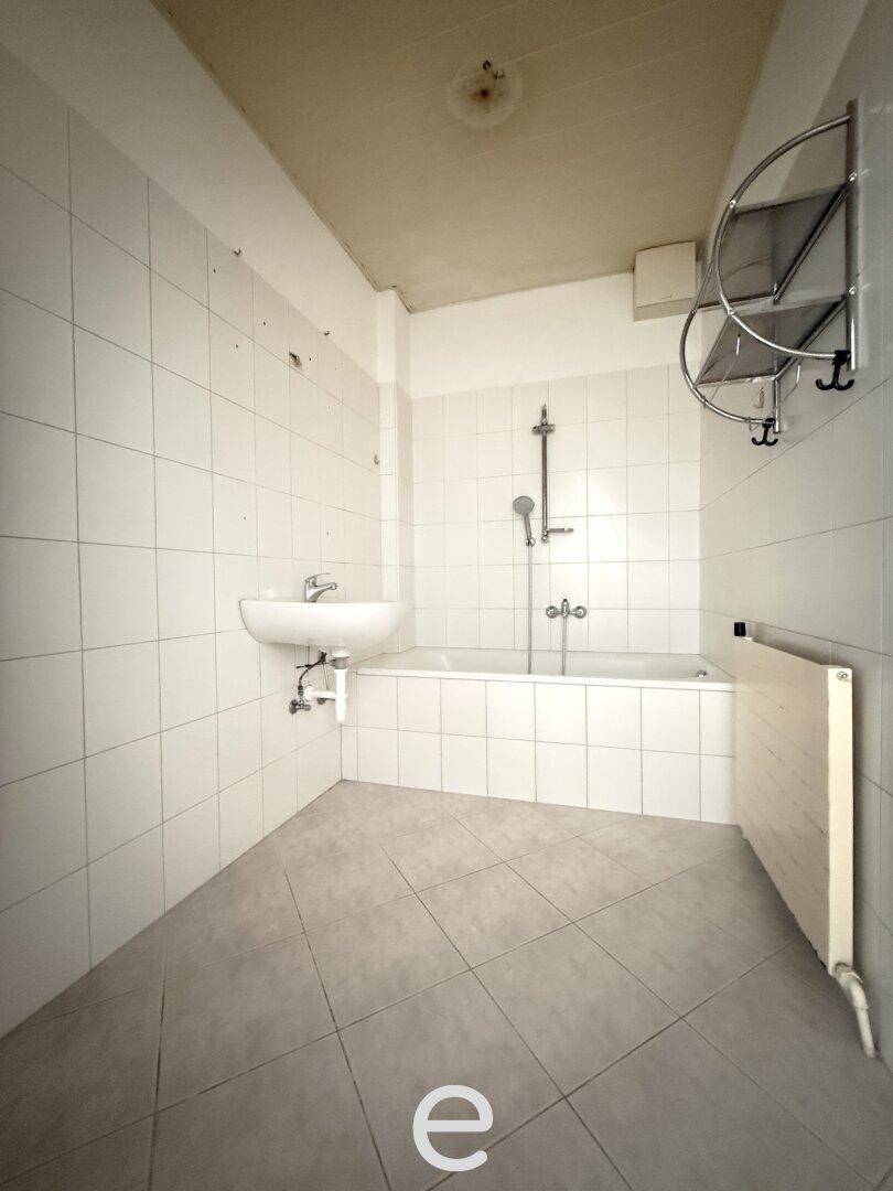 Funktionales Badezimmer mit Badewanne, Waschbecken und weißen Fliesen.