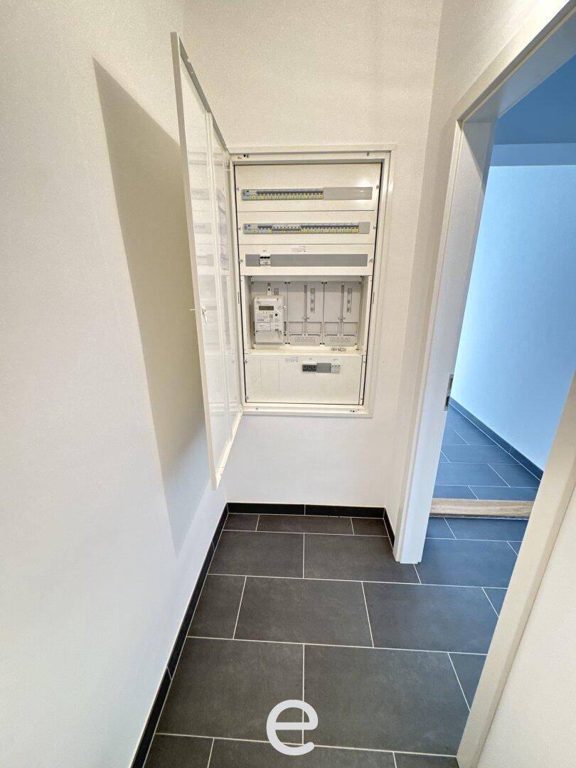 Flur mit modernem Sicherungskasten und dunklem Fliesenboden, der die Elektrik des Hauses zeigt.