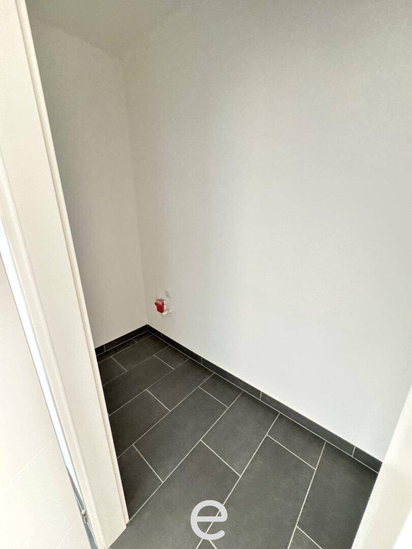 Kleiner Abstellraum mit dunklem Fliesenboden und Anschlussmöglichkeiten für Haushaltsgeräte.