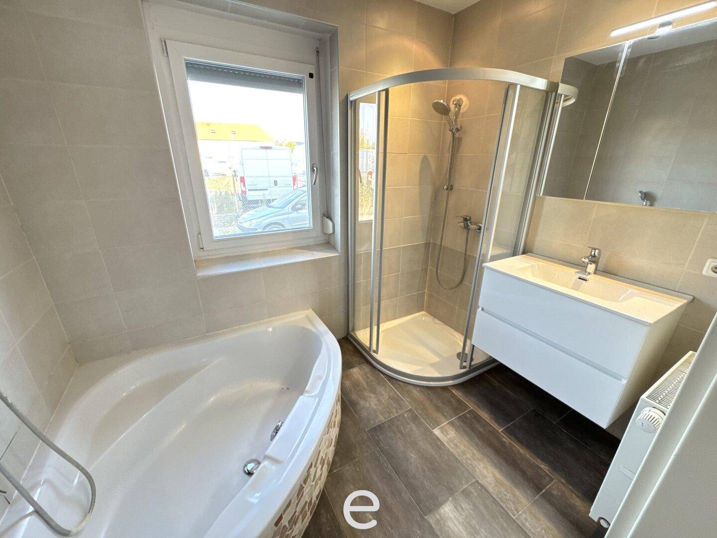 Modernes Badezimmer mit Eckbadewanne, Duschkabine, Einzelwaschbecken und Fenster für Tageslicht.