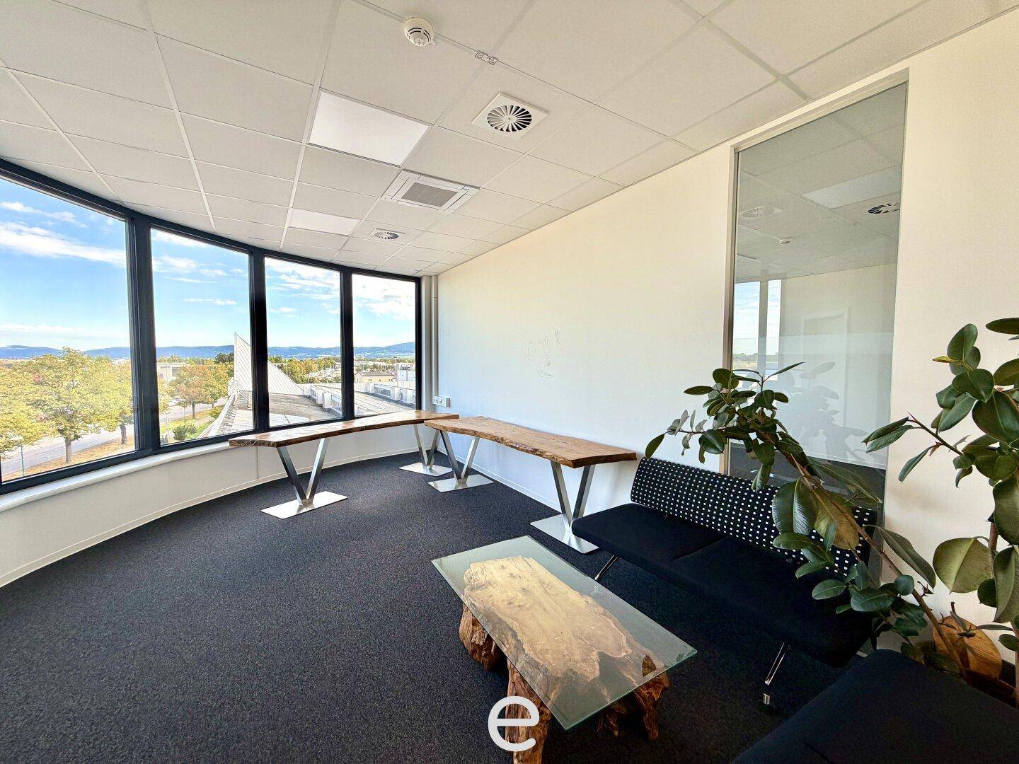 Modernes Büro mit großen Fenstern, die einen weiten Blick bieten, und stilvollen Holztischen.