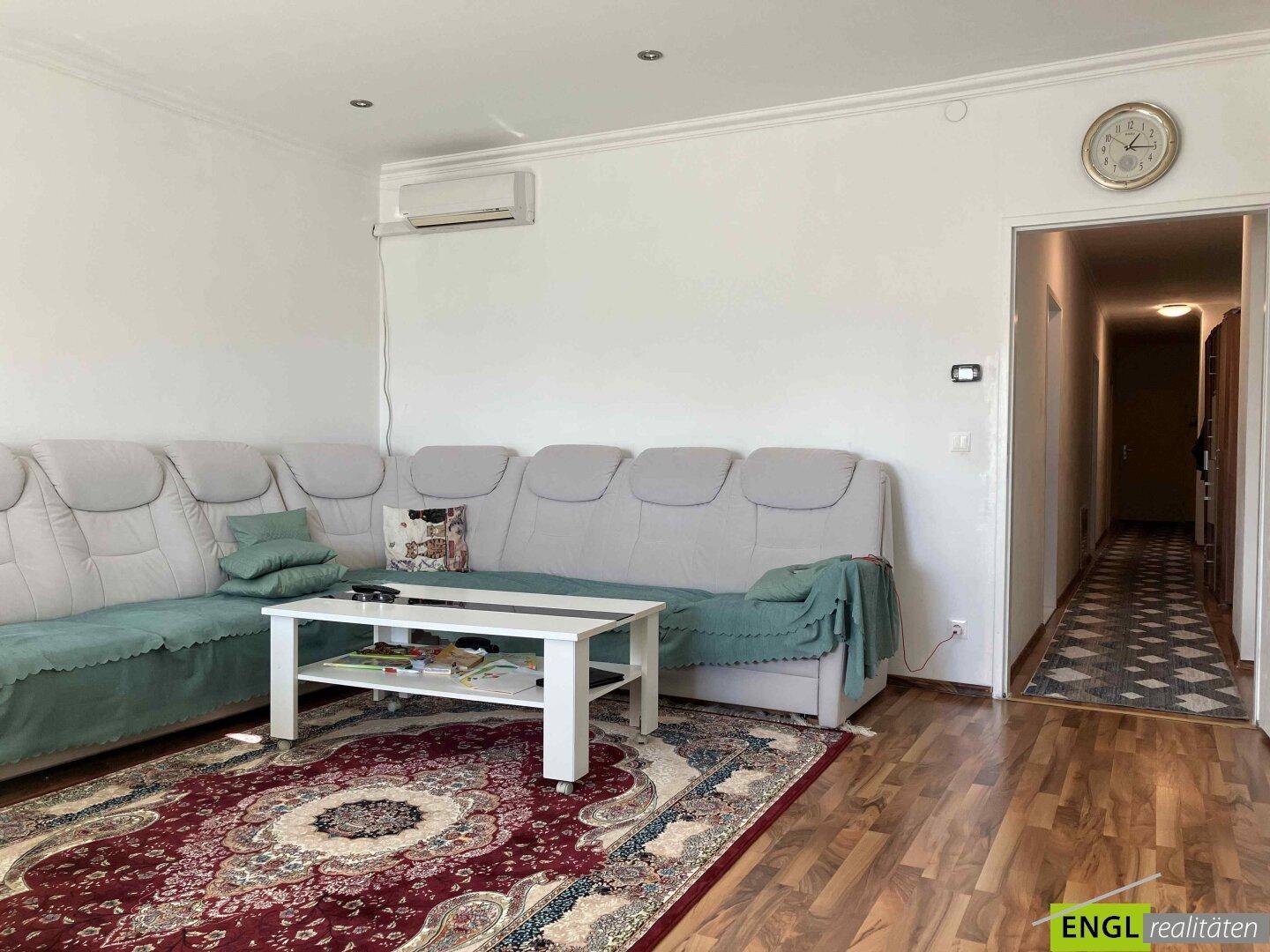 Gemütliches Wohnzimmer mit großem Sofa, Teppich und Klimaanlage.