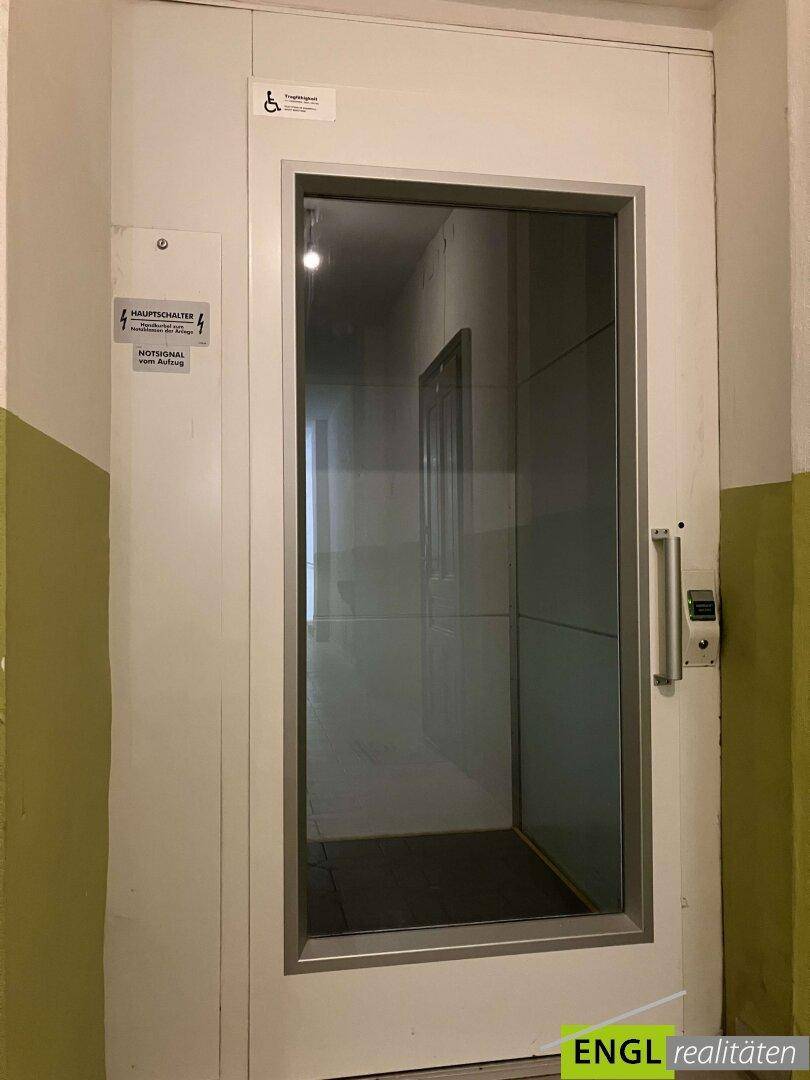 Moderner Aufzug mit Glasfront im Treppenhaus, barrierefrei zugänglich.