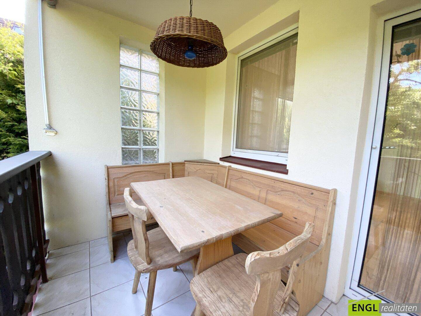 Gemütlicher Balkon mit rustikalen Holzmöbeln und Fliesenboden, ideal für entspannte Stunden im Freien.