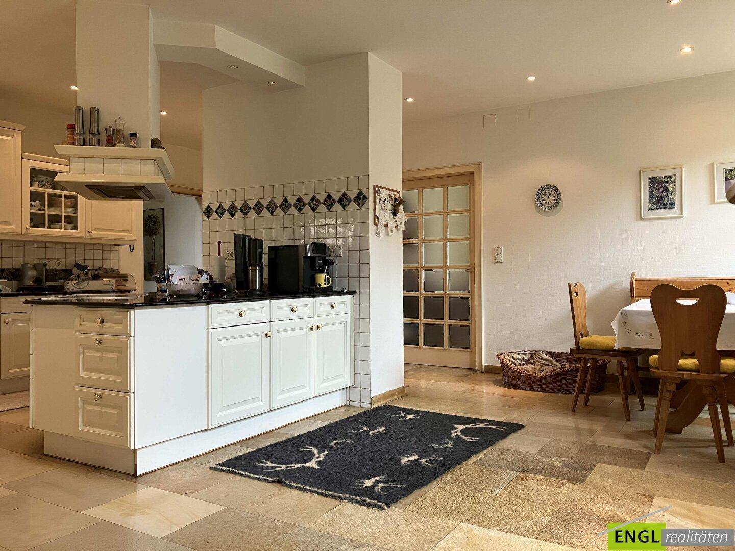 Traditionelle Küche mit weißen Schränken, Fliesenboden und angrenzendem Essbereich.