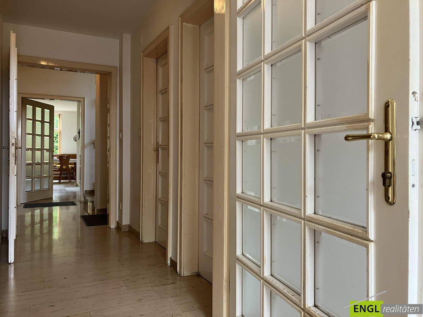 Heller Flur mit mehreren Türen und einem Fliesenboden, der zu weiteren Räumen führt.